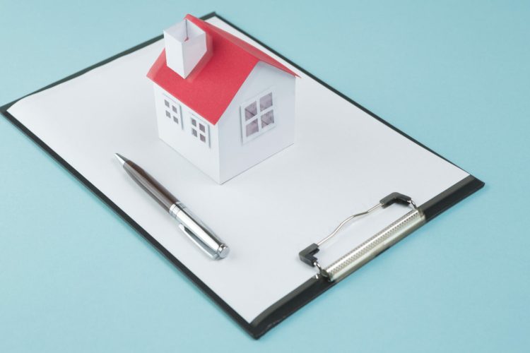 petit-modele-maison-stylo-presse-papier-vierge-fond-bleu